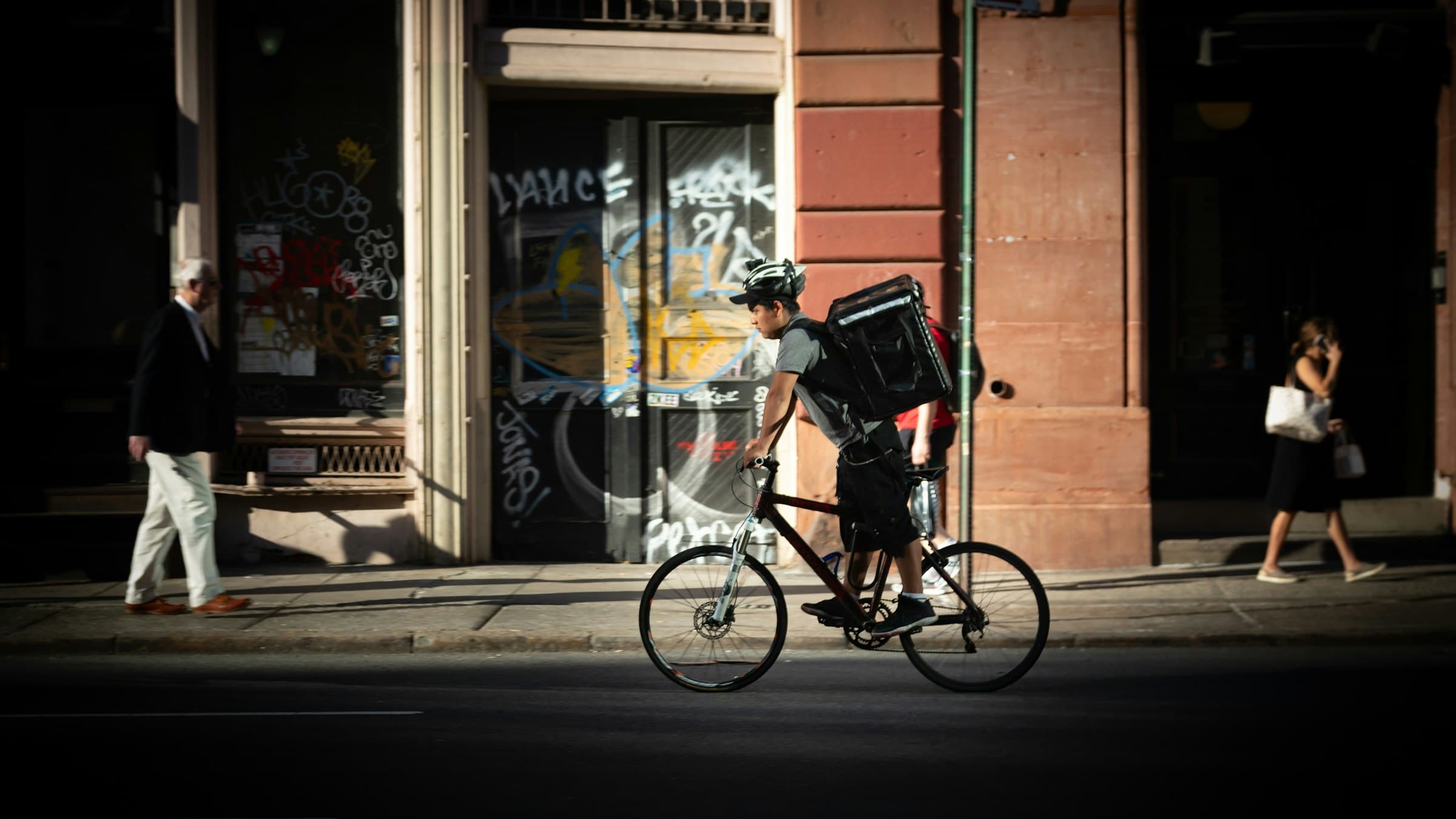 Bike courier riding through the city with an insulated delivery bag