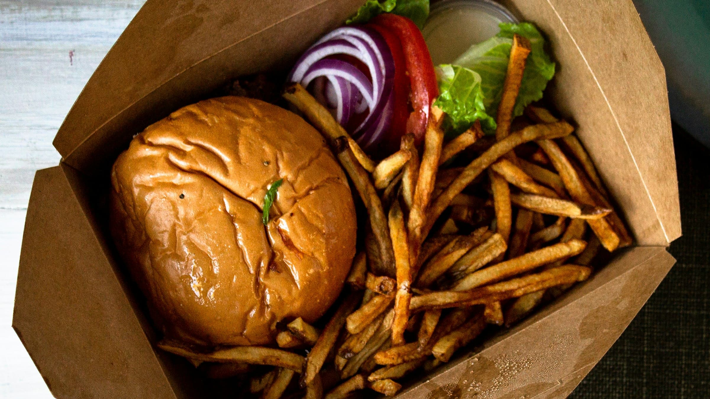 Burger and fries packed in a paper takeout box